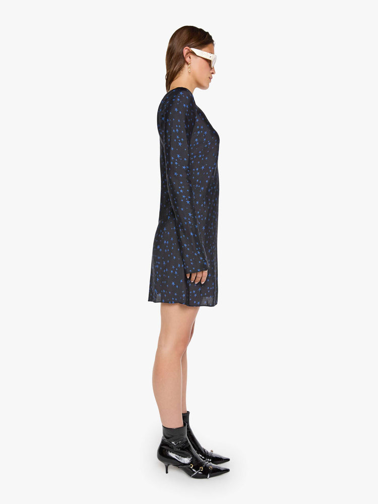 Side view of a woman wearing  a bias-cut mini dress with a wide crewneck, long sleeves, a thigh-length hem and a pull-on, zipless design. 