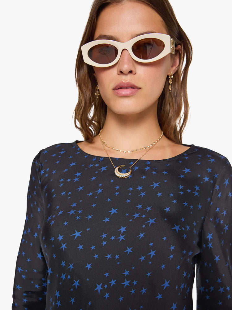 Close up view of a woman wearing  a bias-cut mini dress with a wide crewneck, long sleeves, a thigh-length hem and a pull-on, zipless design. 