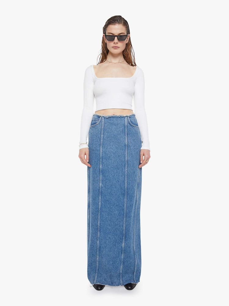 Front view of a med blue high-waisted skirt is designed with a frayed waistband and hem, back-zip closure, pintuck details down the front and a loose fit.