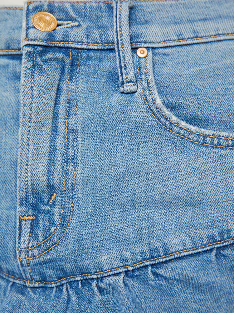 Swatch view of a woman in a light blue denim mini skirt with a zip fly, angled ruffles and a frayed hem.