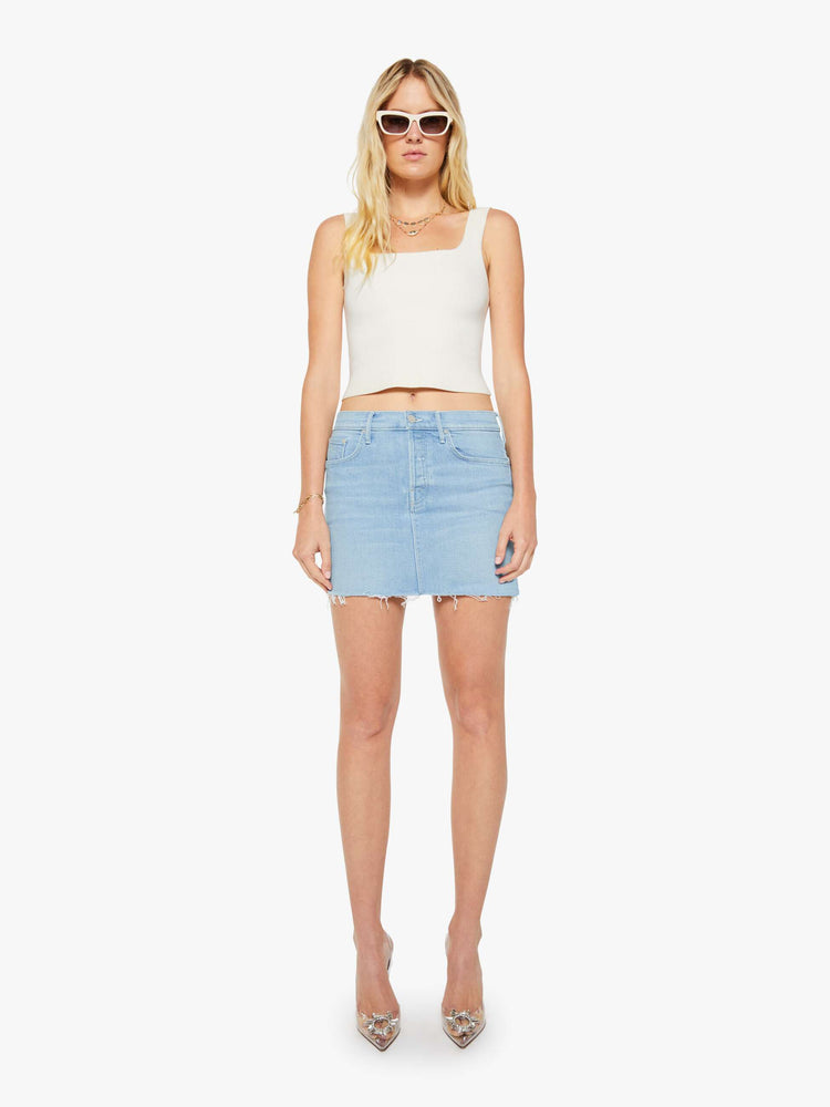 Front view of a woman in light blue a low-slung mini skirt with a button fly and a raw, frayed hem.