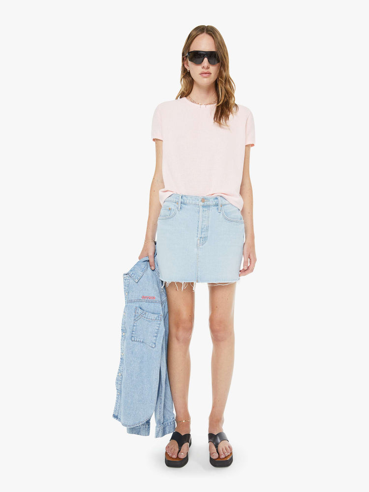Front view of a woman in a light blue low-slung denim mini skirt with a button fly and a raw, frayed hem.