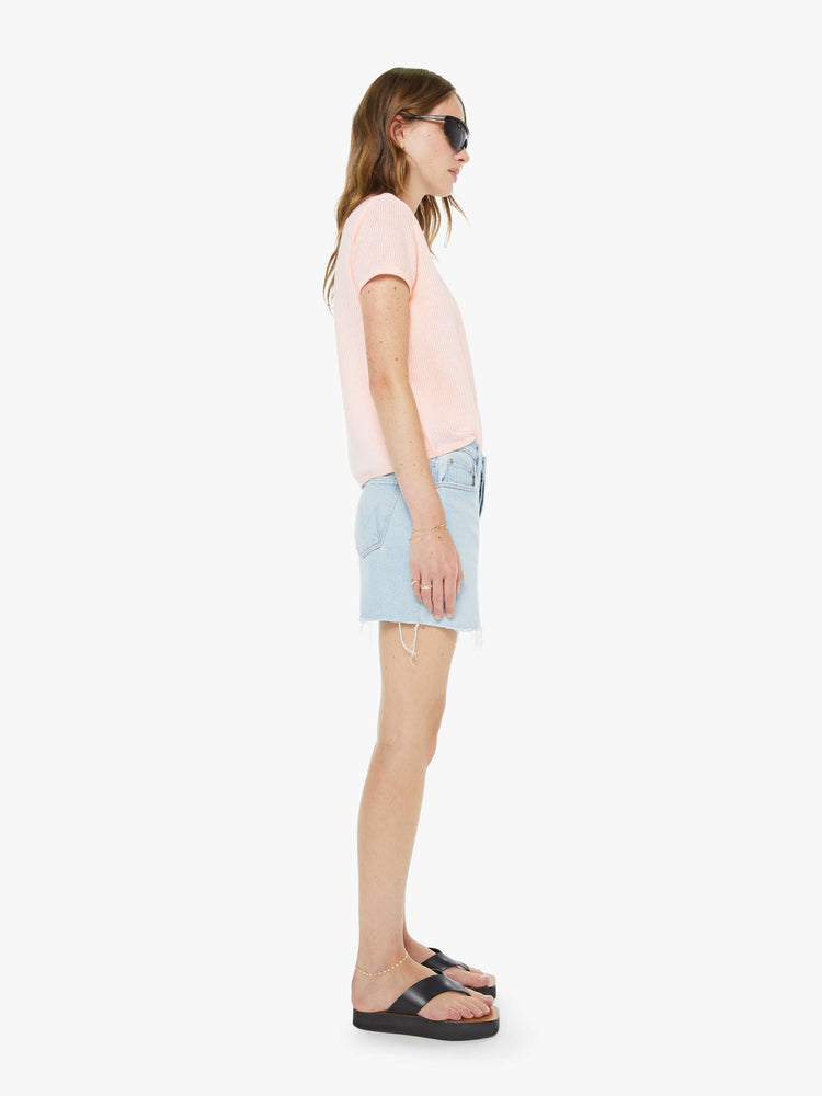 Side view of a woman in a light blue low-slung denim mini skirt with a button fly and a raw, frayed hem.