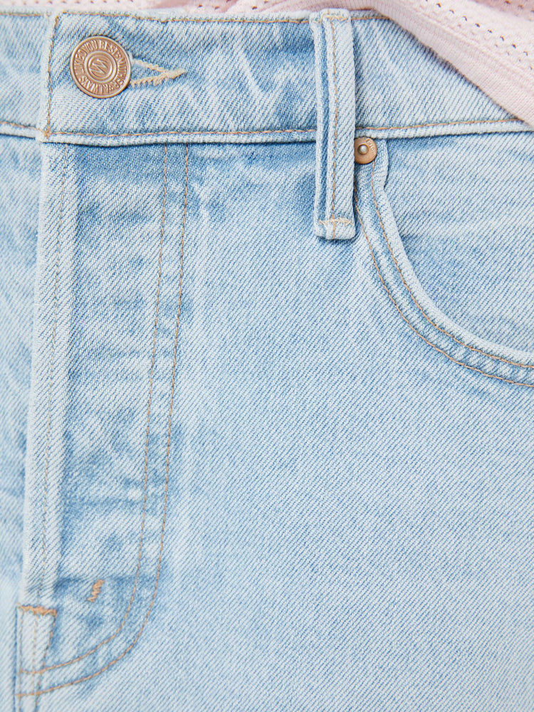 Swatch view of a woman in a light blue low-slung denim mini skirt with a button fly and a raw, frayed hem.