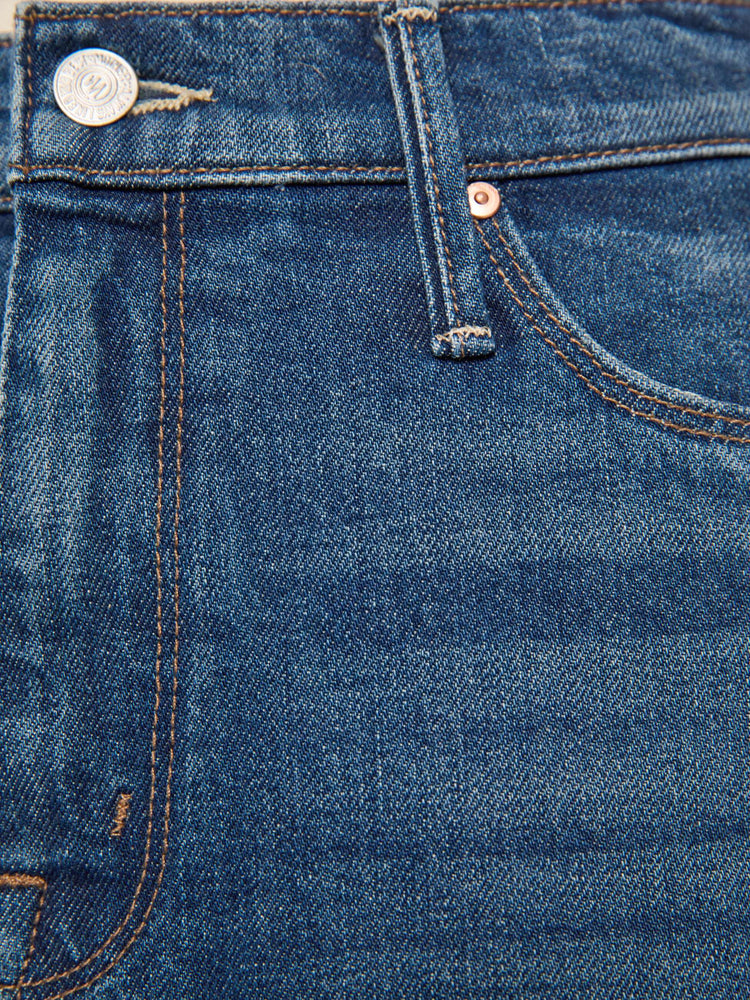 Swatch view of a woman in a mid blue denim midi skirt with a zip fly, frayed hem and an A-line fit.