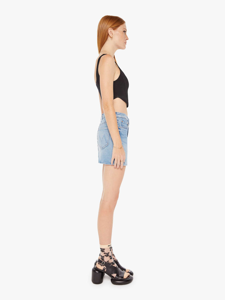 Side view of a womens light blue wash denim skirt featuring a relaxed mid rise and a short clean hem.