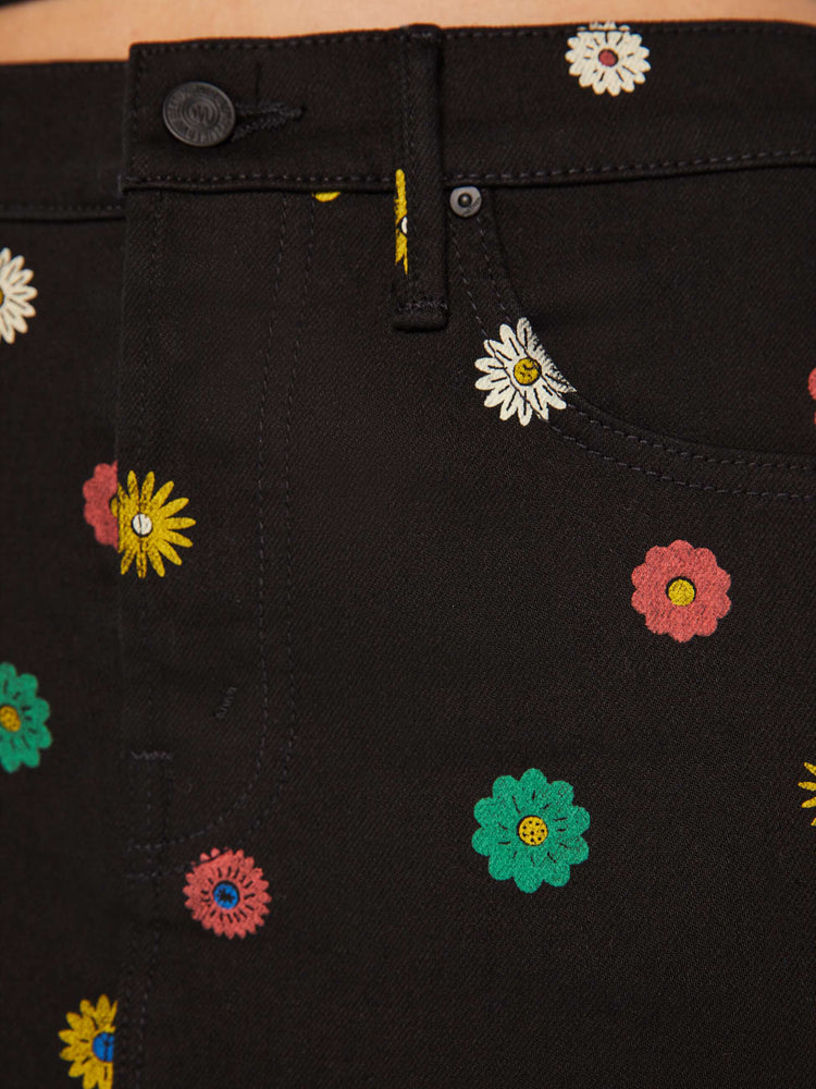 Swatch view of a woman in denim mini skirt with a high rise, button fly, slim fit and thigh-grazing hem in a black shade with colorful printed daisies throughout.