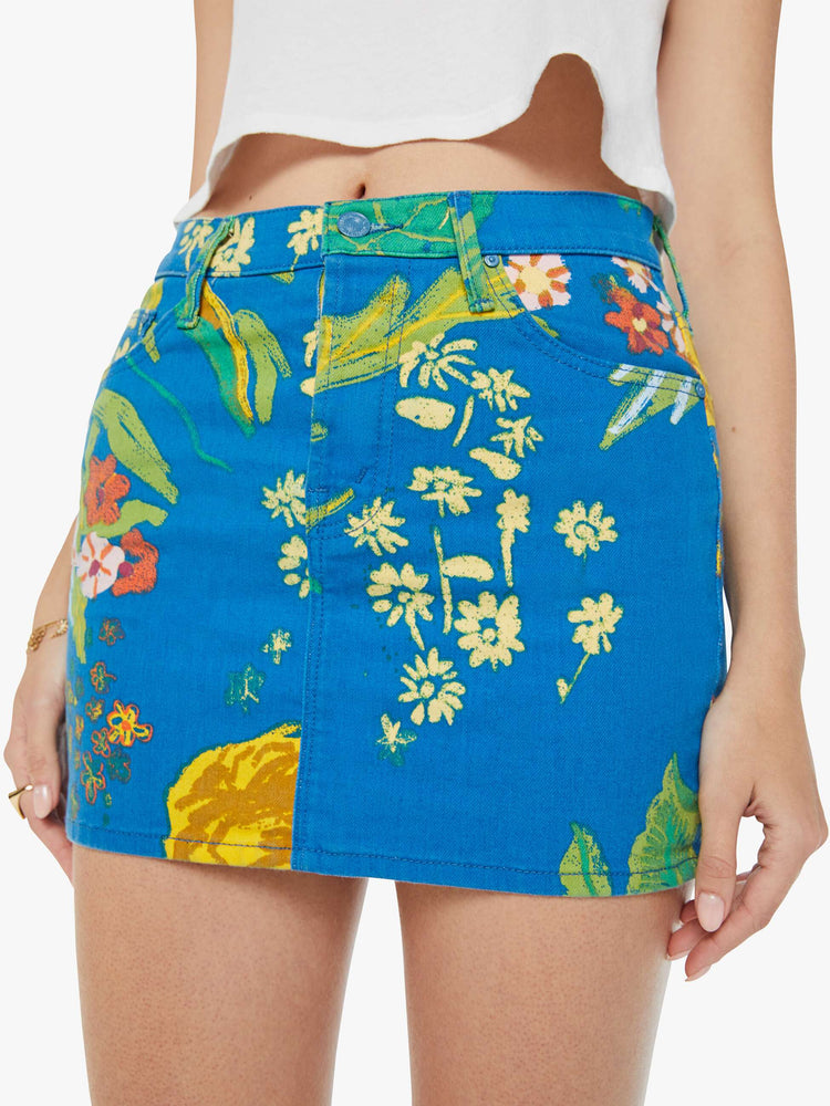 Swatch view of a woman in a bright blue mini skirt with an oversized tropical floral print, high rise, button fly, slim fit and thigh-grazing hem. 