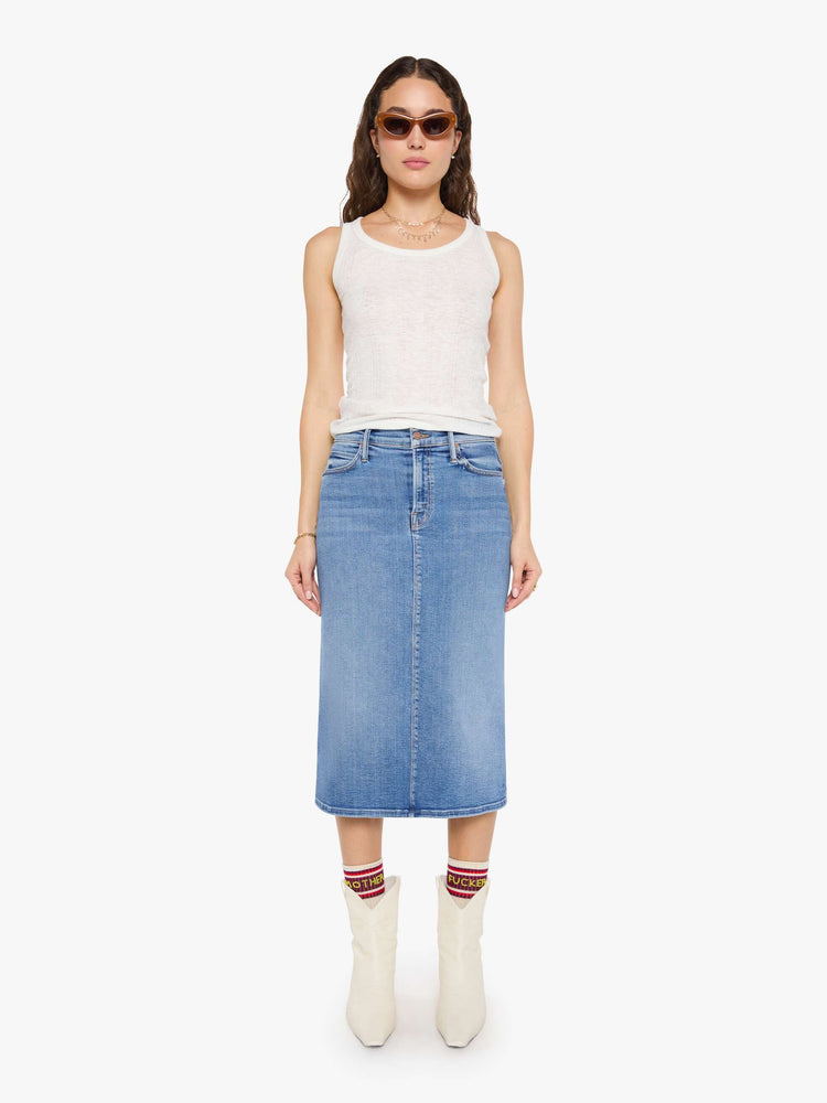 Front view of a woman in med blue denim midi skirt with a zip fly and an A-line fit.