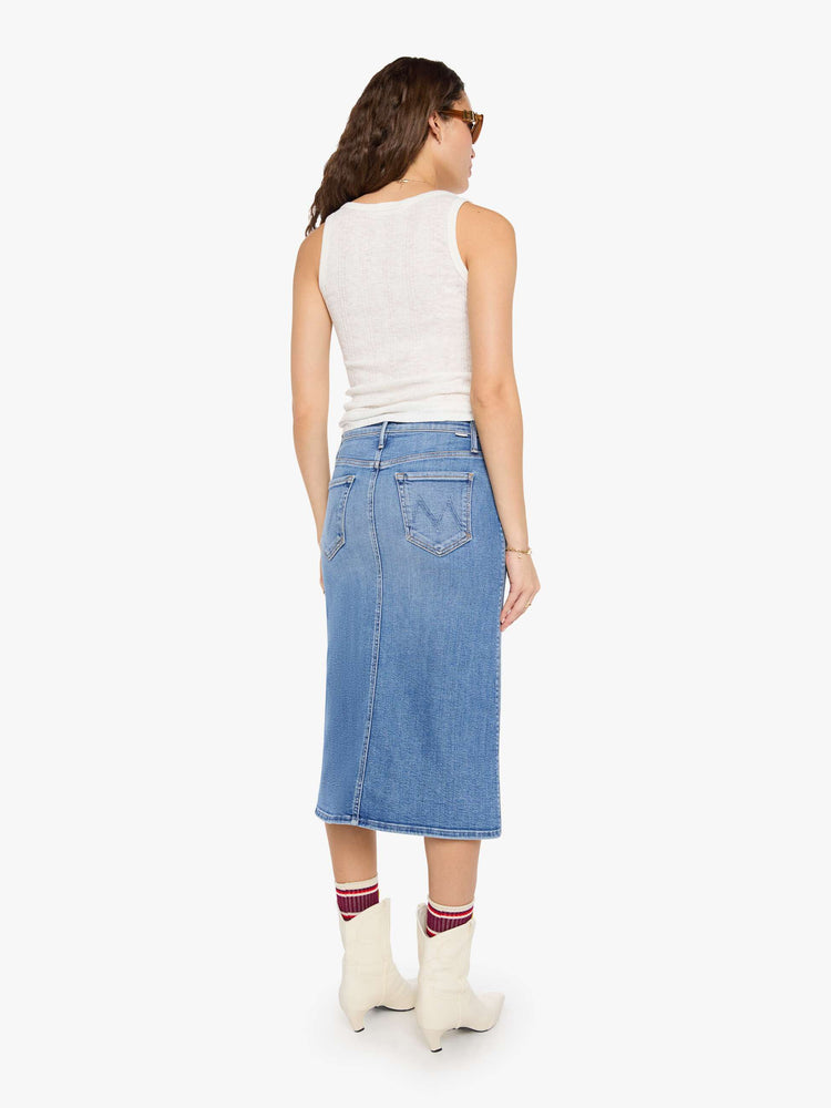 Back view of a woman in med blue denim midi skirt with a zip fly and an A-line fit.