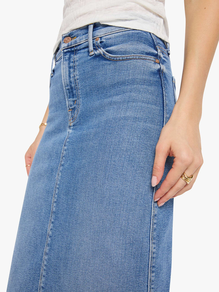 Close up view of a woman in med blue denim midi skirt with a zip fly and an A-line fit.
