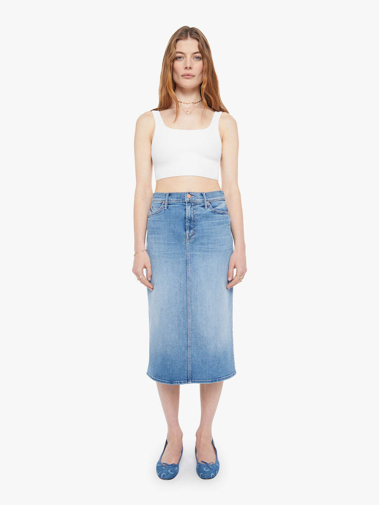 Front view of a woman in a light blue  high-waisted denim midi skirt with a zip fly, A-line fit and calf-length hem. 