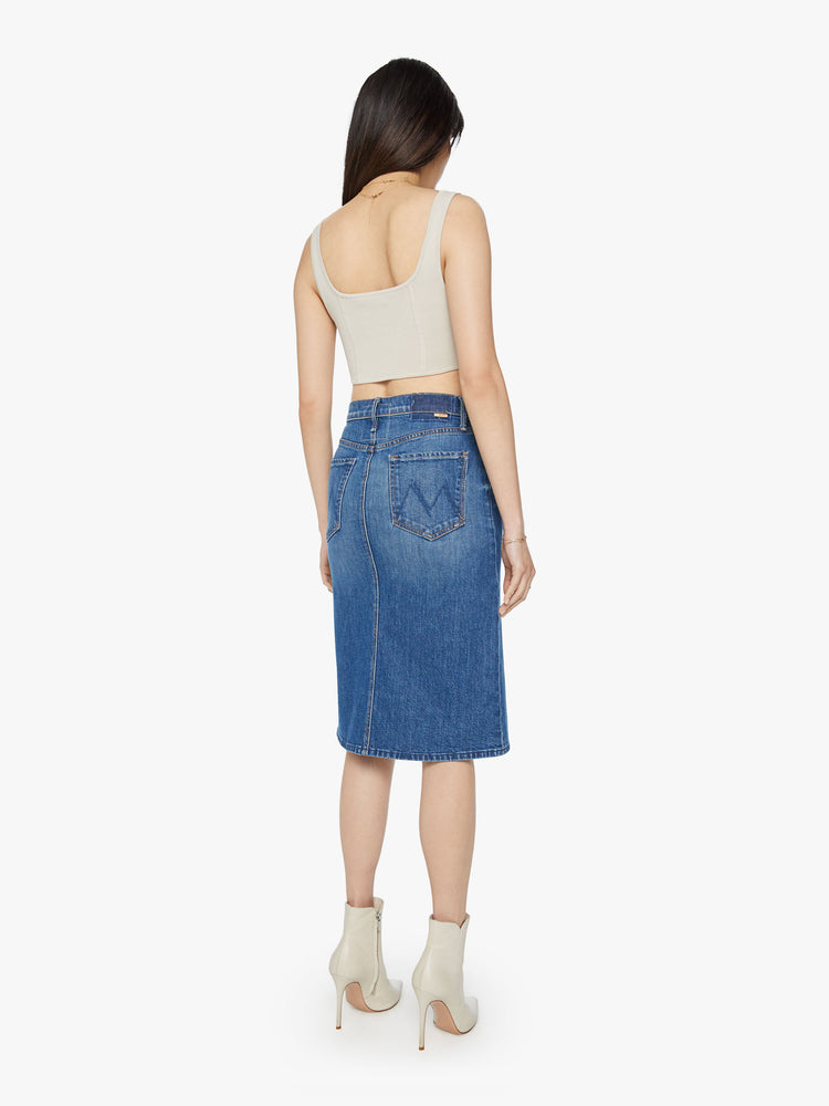 Back view of a woman denim midi skirt with a knee-length hem and a slouchy fit designed to sit lower on the hips in a classic blue wash.