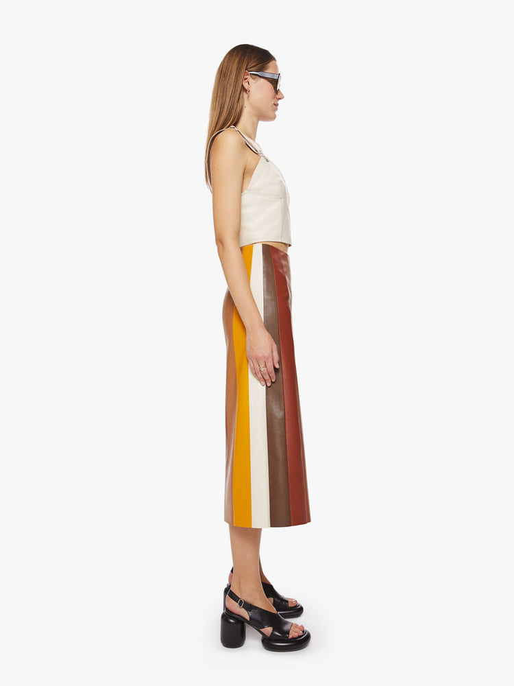 Side view of a woman colorblocked midi skirt with a high rise, loose fit and a calf-grazing hem in a faux leather.