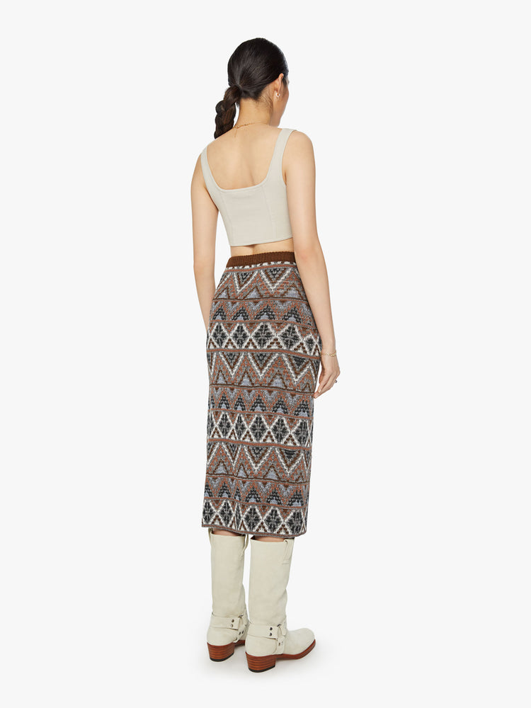 Back view of a woman knit midi skirt with a high-rise, thigh-high side slit and a straight fit in metallic shades of brown, grey and white.