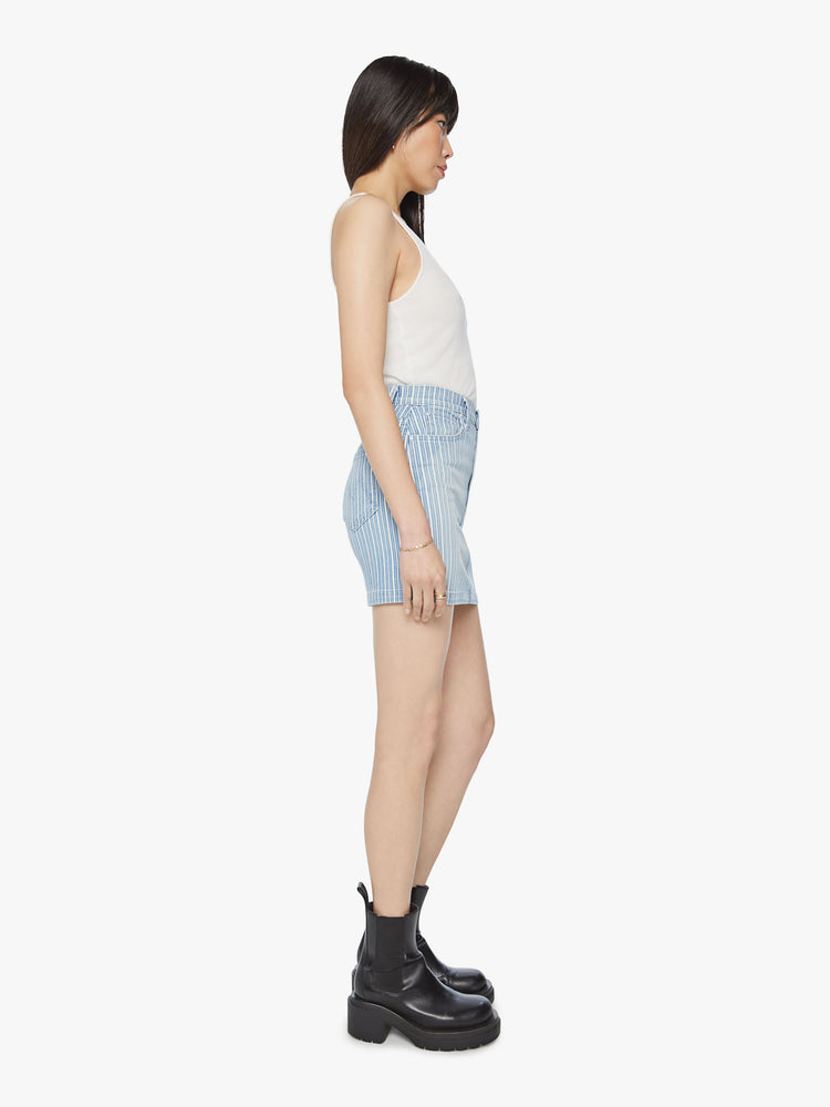 Side view of a woman high waisted mini skirt with slit pockets and a playfully short hemline in a light blue and white striped denim.