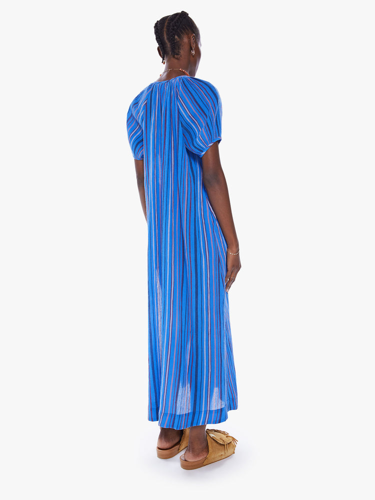 Back view of a woman maxi dress with a V-neck, short puffed sleeves, side slits in a blue stripe pattern.