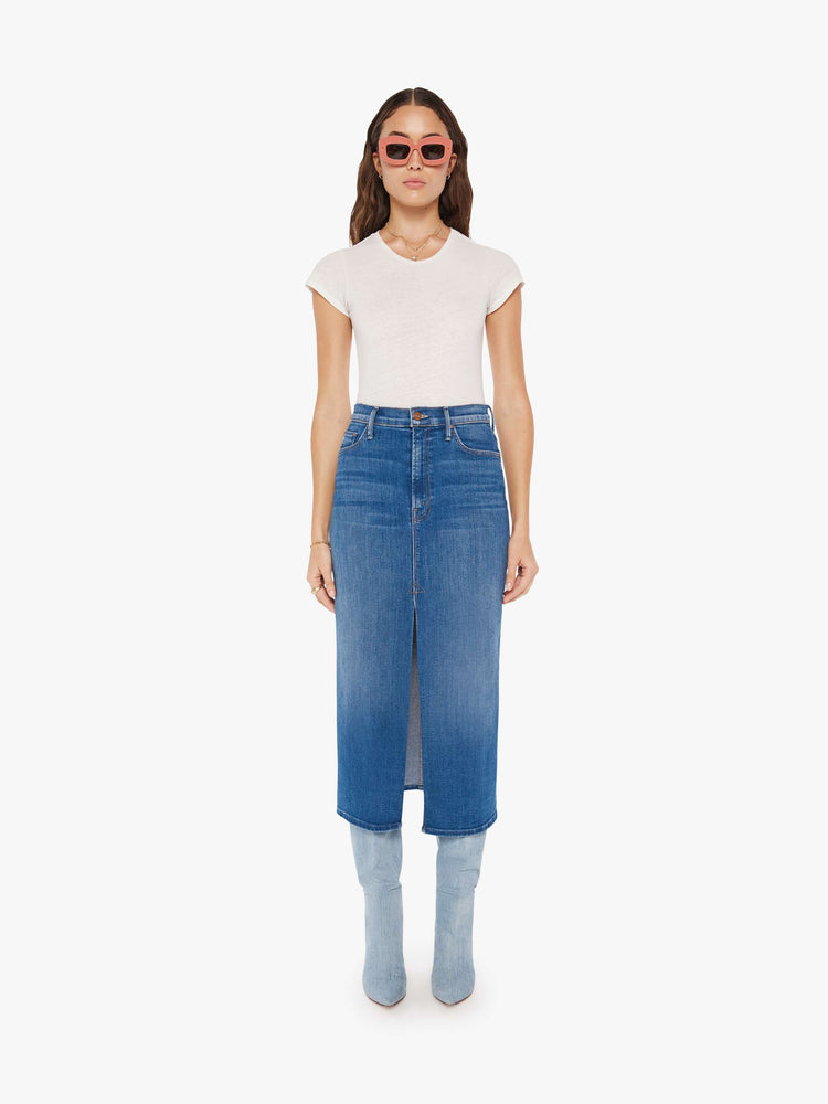 Front view of a woman denim pencil skirt with a high rise, narrow fit and a thigh-high front slit in a mid blue wash.