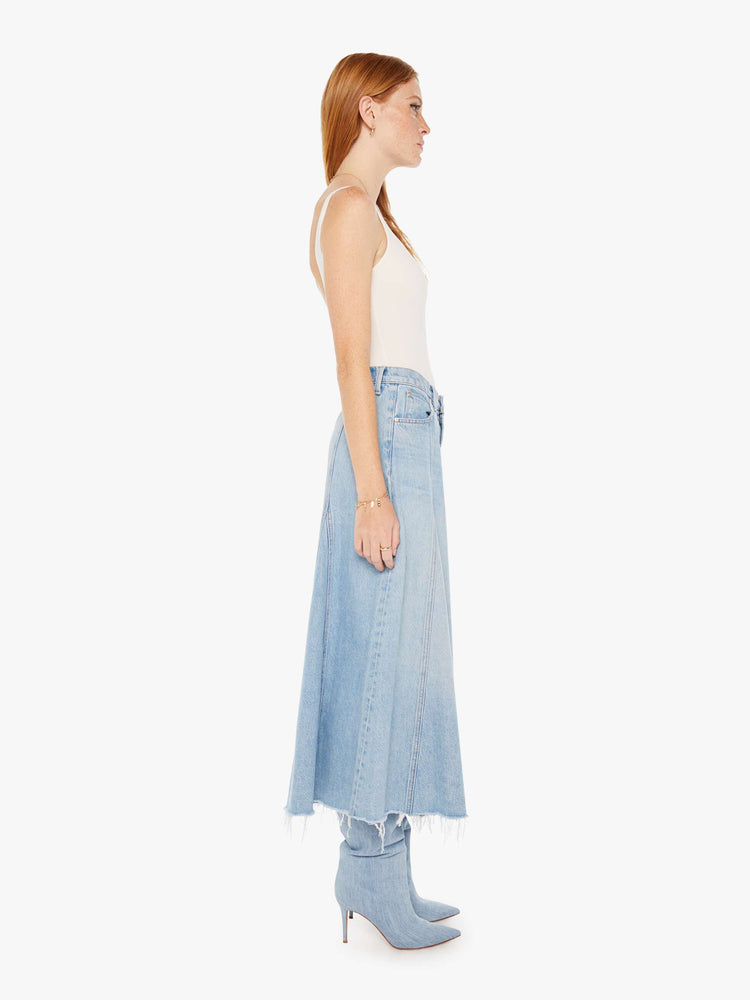 Side view of a womens light blue wash denim skirt featuring a high rise and frayed hem.