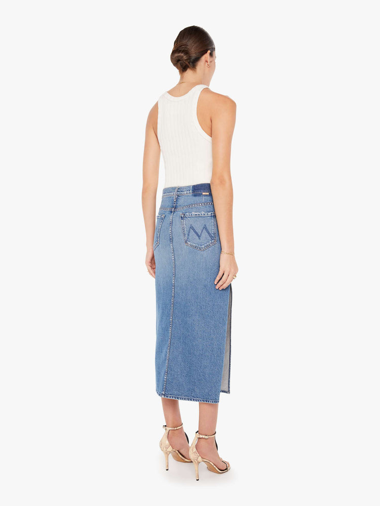 Back view of a womens medium blue wash denim skirt featuring a high rise and a high side slit.