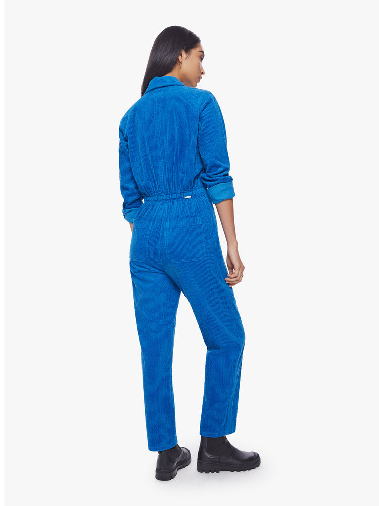 Back view of a woman zip-up jumpsuit with a collared neck, long sleeves, patch pockets and an ankle-length inseam in a bright blue corduroy.
