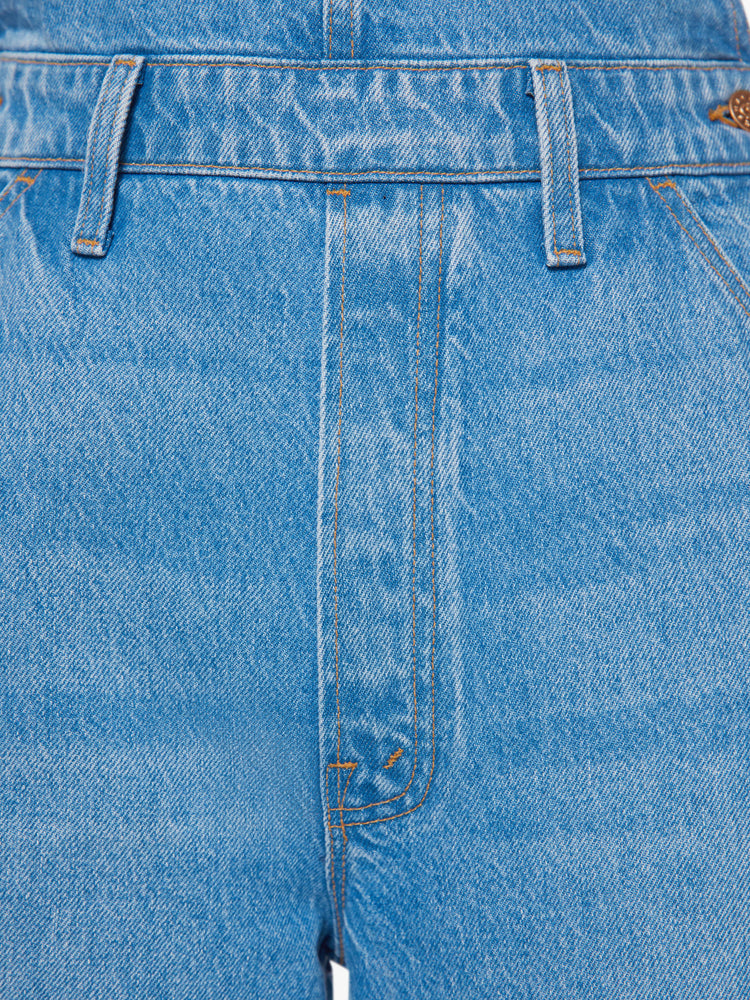 Swatch view of a woman mid-blue wide leg overalls feature a loose, full leg, a hammer loop and a 32-inch inseam.