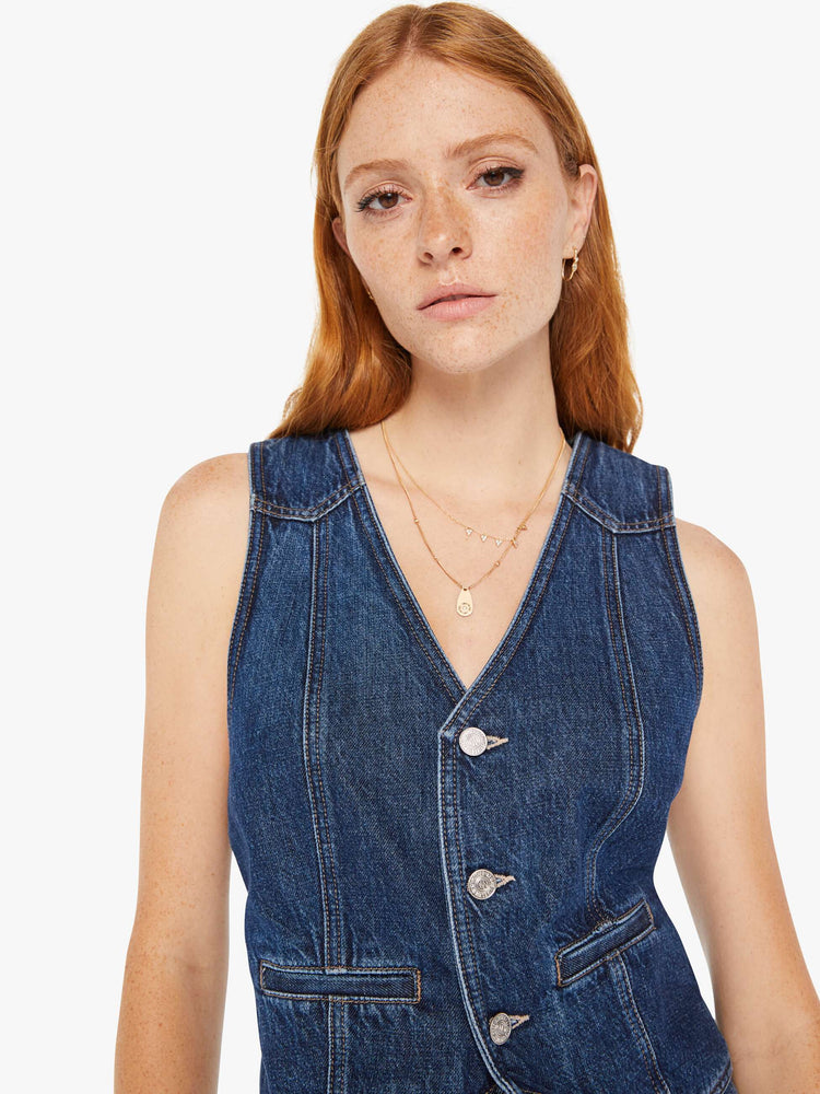 Front close up view of a womens denim vest in a dark blue wash.