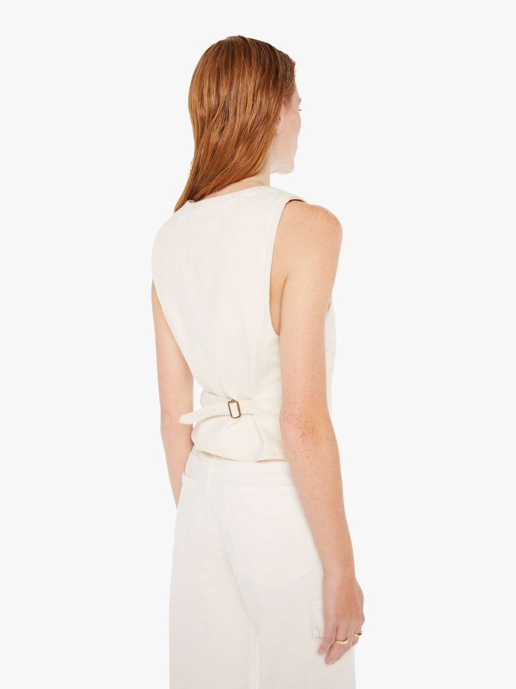 Back view of a woman wearing an off white denim vest featuring a tightening buckle..