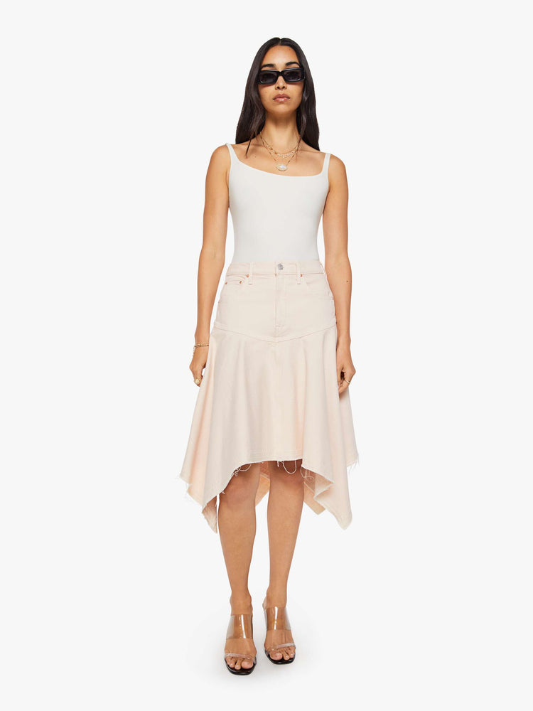 Front view of a woman in pure peach high-waisted midi skirt that's fitted at the hips with a zip fly, flowy, gathered skirt and an uneven, frayed hem.