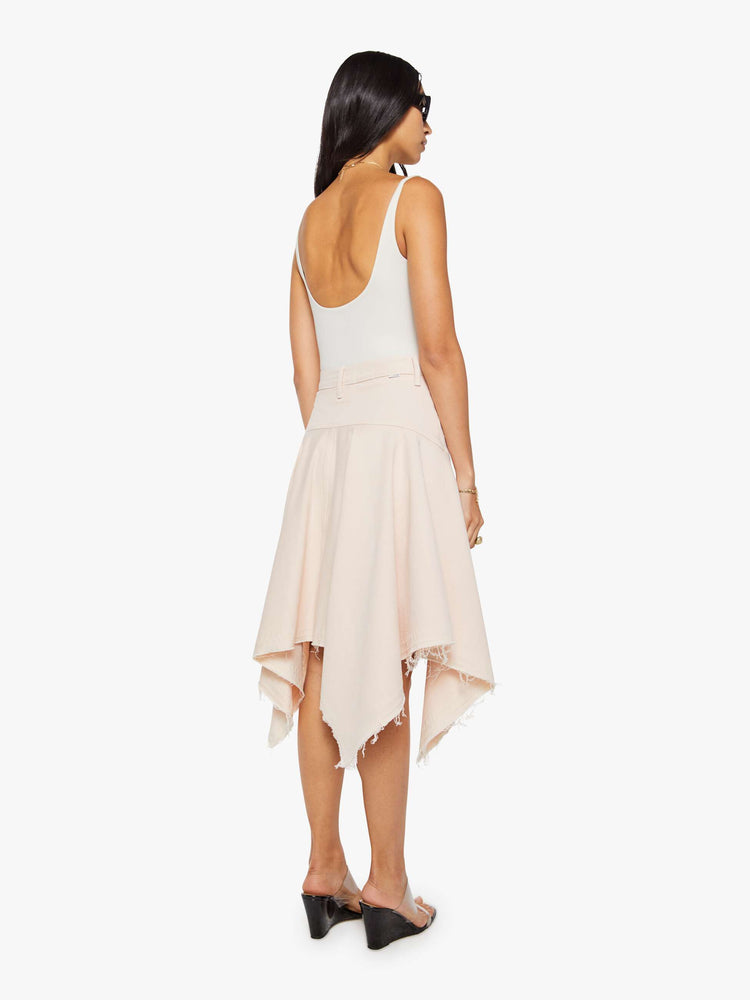 Back view of a woman in pure peach high-waisted midi skirt that's fitted at the hips with a zip fly, flowy, gathered skirt and an uneven, frayed hem.