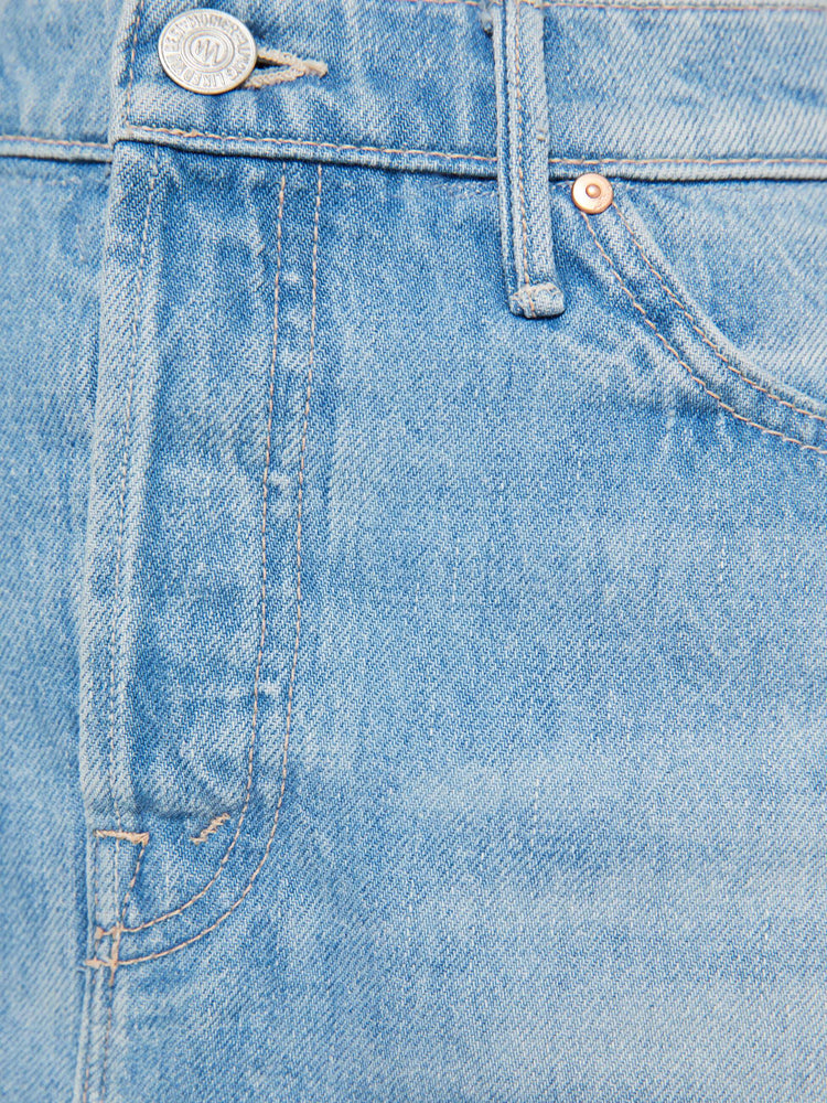Swatch view of a woman in a light blue denim maxi skirt with a high rise, button fly, angled frayed hem and sheer lace slip underneath that hits at the ankles. 