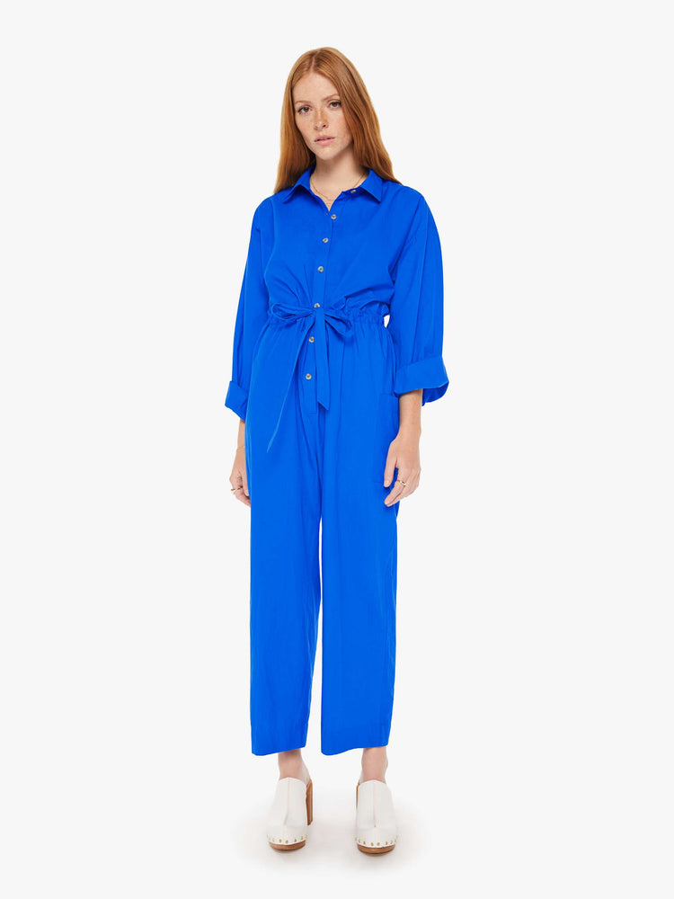 Front view of a woman royal blue lightweight collared jumpsuit with longsleeves, a tied waist, cargo patch pockets and an ankle-length straight leg.