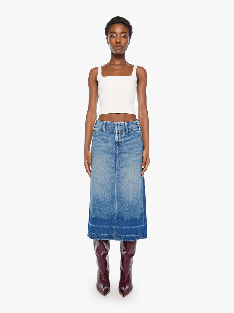 Front view of a woman in a mid blue skirt is designed with an extra-wide waistband, zip closure, A-line fit and an undone hem.