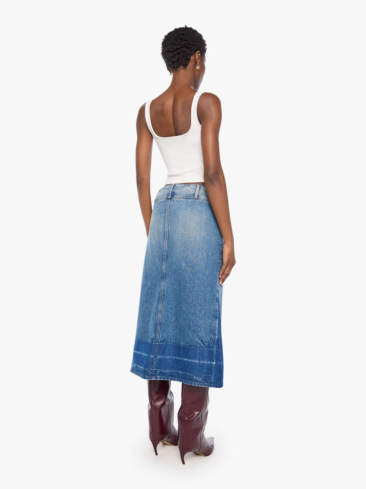 Back view of a woman in a mid blue skirt is designed with an extra-wide waistband, zip closure, A-line fit and an undone hem.