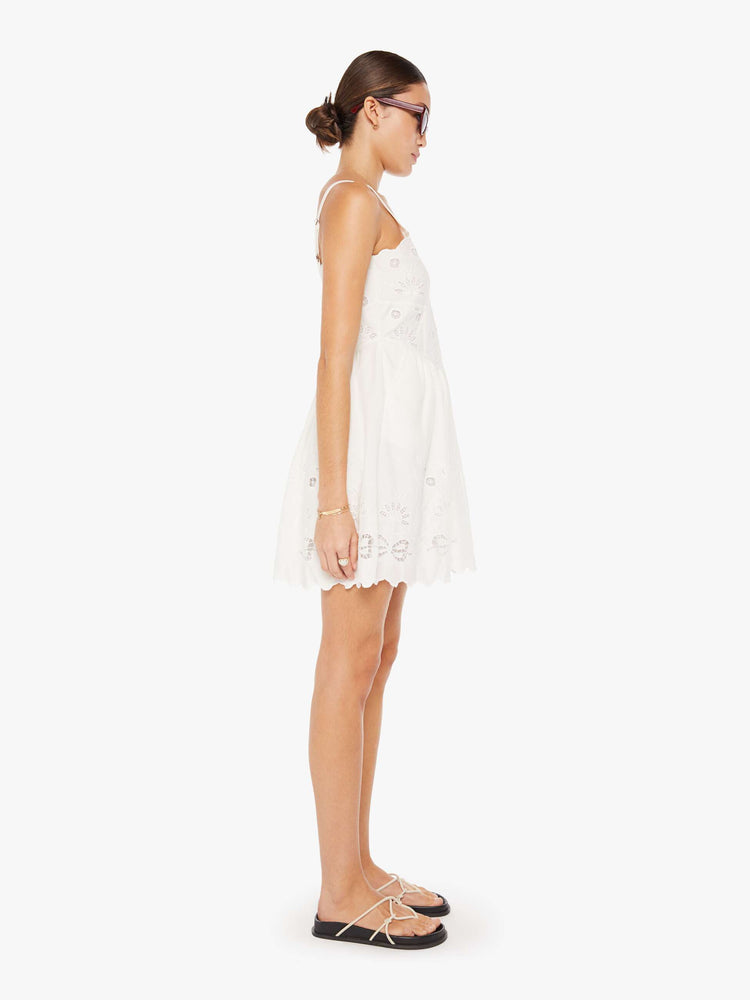 Side view of a womens white mini dress featuring embroidered details and eyelets.