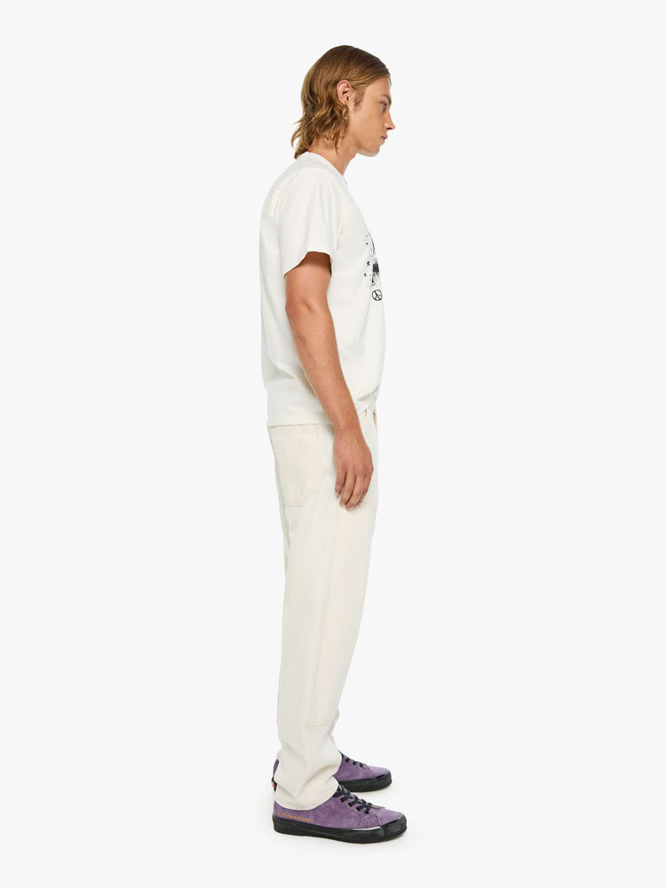 Side view of a classic pant with slit pockets, a zip fly, workwear-inspired patches at the knees, a hammer loop and a loose leg.