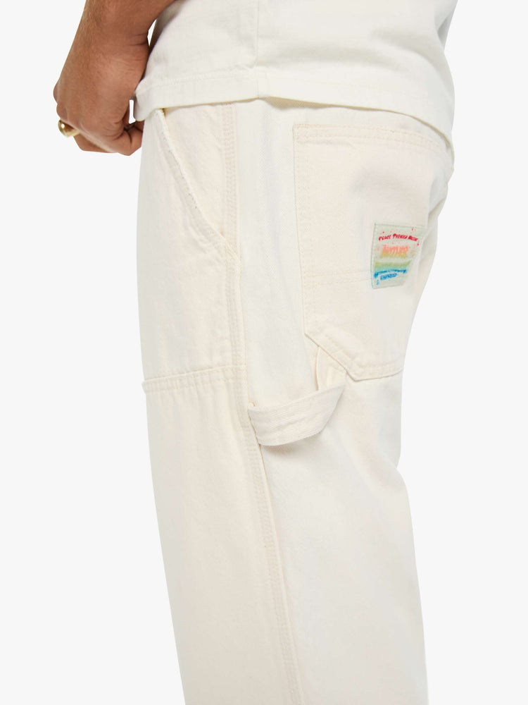 Close up view of a classic pant with slit pockets, a zip fly, workwear-inspired patches at the knees, a hammer loop and a loose leg.