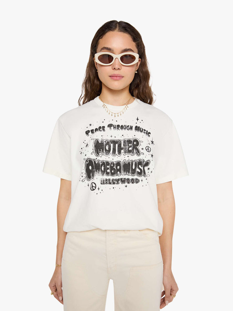 WOMAN front view in a  white top with a MOTHER's spin on the classic Amoeba Music logo in black on the front.