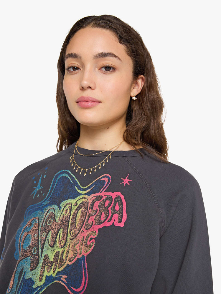 Close up view of woman faded black, the sweatshirt features a colorful Amoeba Music graphic and MOTHER's name on the front.