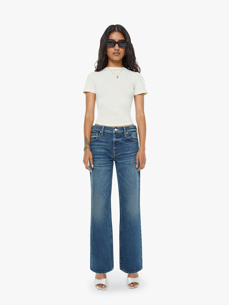 Front view of a petite woman in a  straight leg with a bit of a kick, the jean features a mid rise, full-length inseam and clean hem in a classic blue.