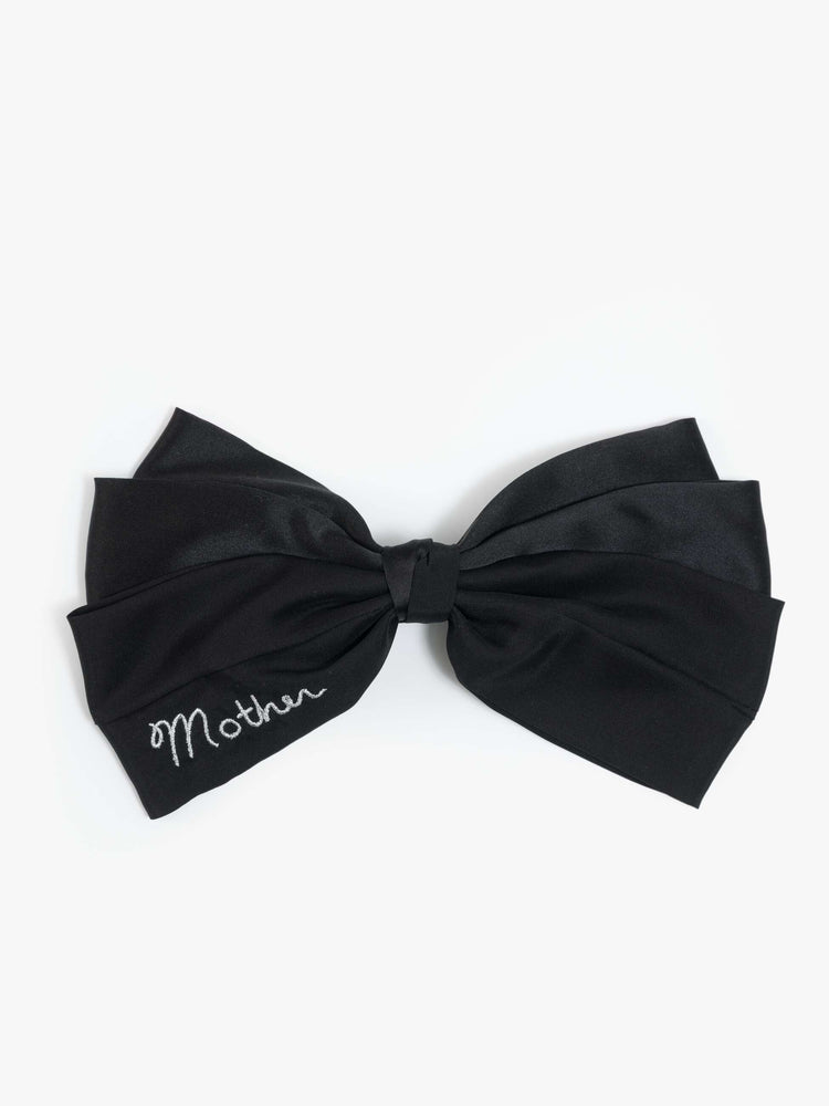 Flat view of a woman in a black hair bow that fastens with a metal barrette so you can clip it on.
