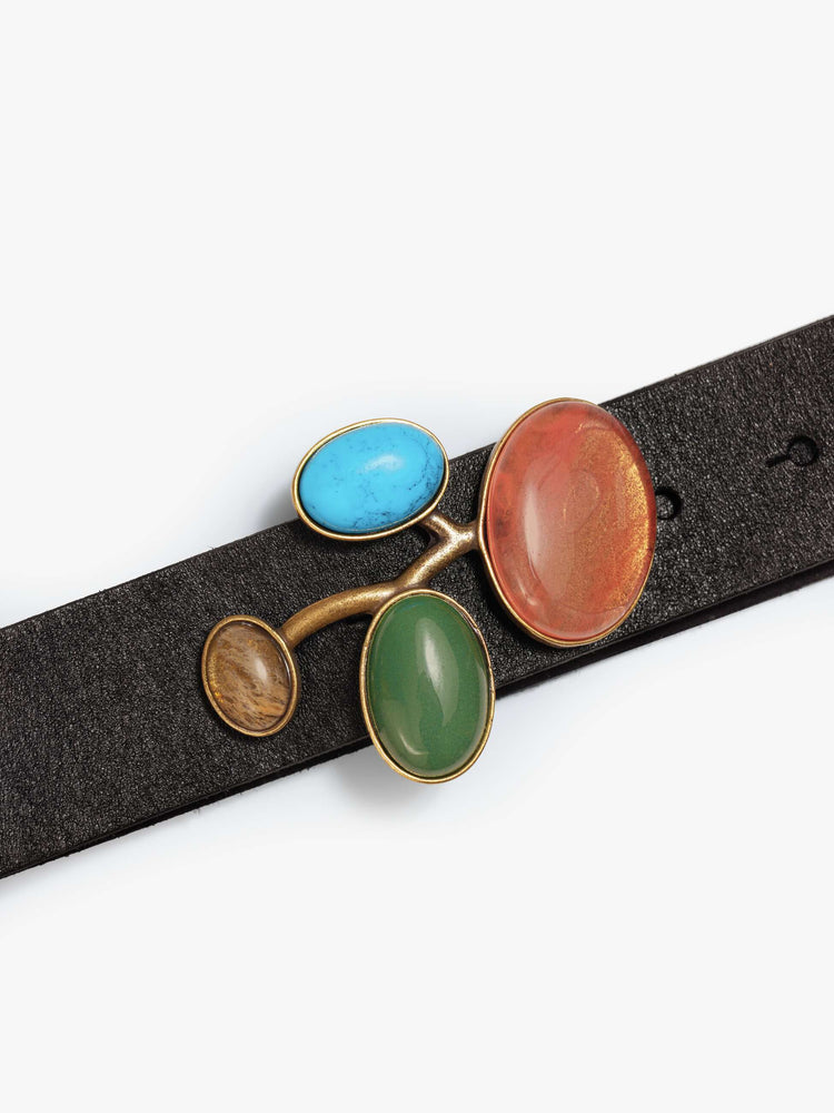 Close up  view of a black leather belt with a chunky metal buckle detailed with turquoise, amber, green and pale yellow stones.