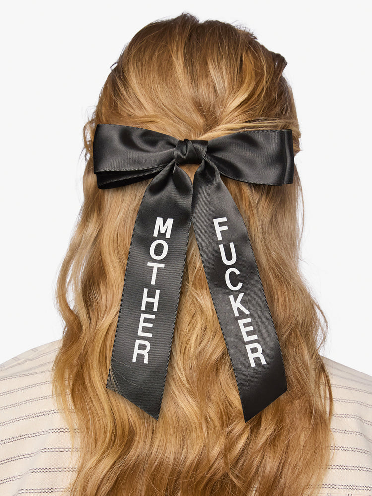 On model black satin-feel hair bow that looks sweet but says otherwise—with MOTHER on one tail and FUCKER on the other.