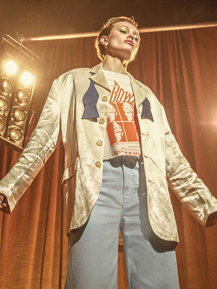 Bowie editorial image of a woman wearing a white and orange graphic Bowie tee  under a satin blazer.