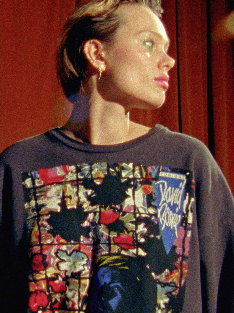 Bowie editorial image of a woman wearing a black crew neck sweatshirt with a vintage inspired Bowie graphic.