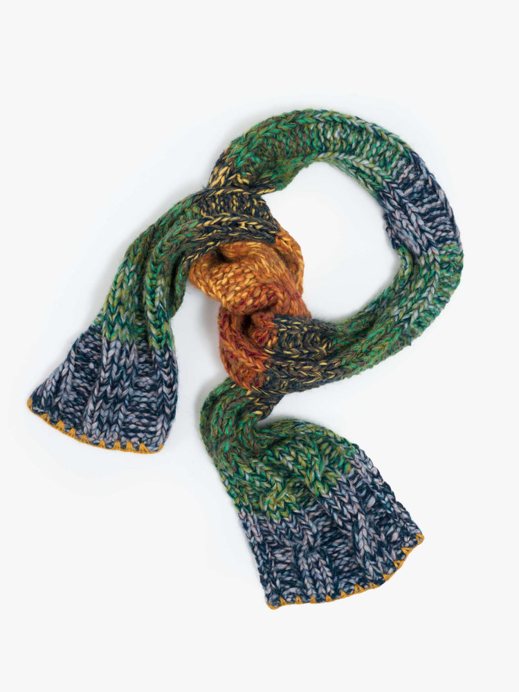 Flat view of a wide, chunky scarf is made from a blend of alpaca and merino wool in a rainbow stripe pattern with cable knit details.