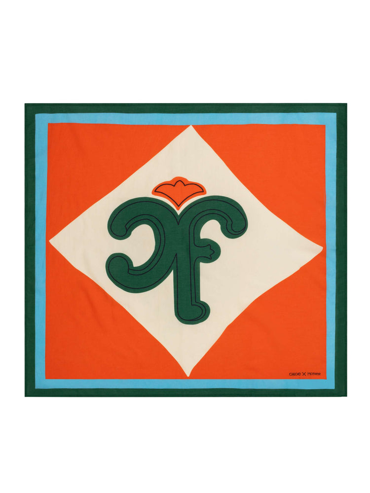 Flat view of a red with green and blue trim square scarf can be worn as a neck tie, hair accessory or tied on a bag. 