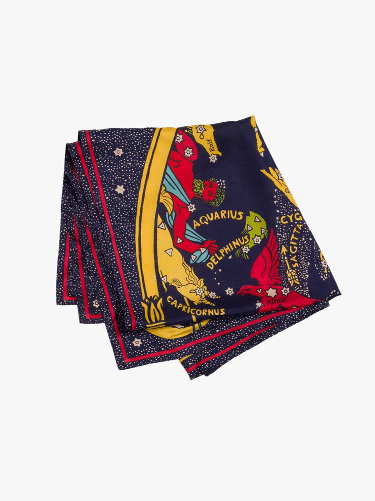 Folded flat view of a woman holding a navy graphic map of cosmos oversized 46-inch square scarf can be worn around the shoulders, on the waist or tied on a bag.