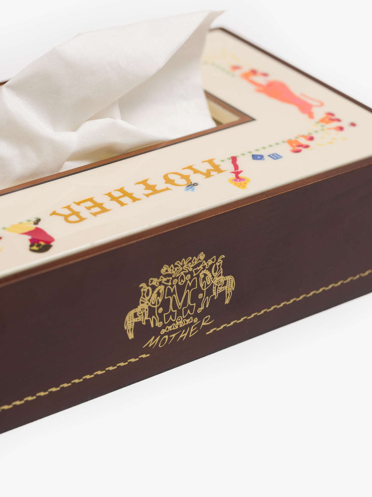 A pine wood tissue box cover designed in brown and off-white with a vinyl-printed top featuring doodles and MOTHER's name in gold along the side. 