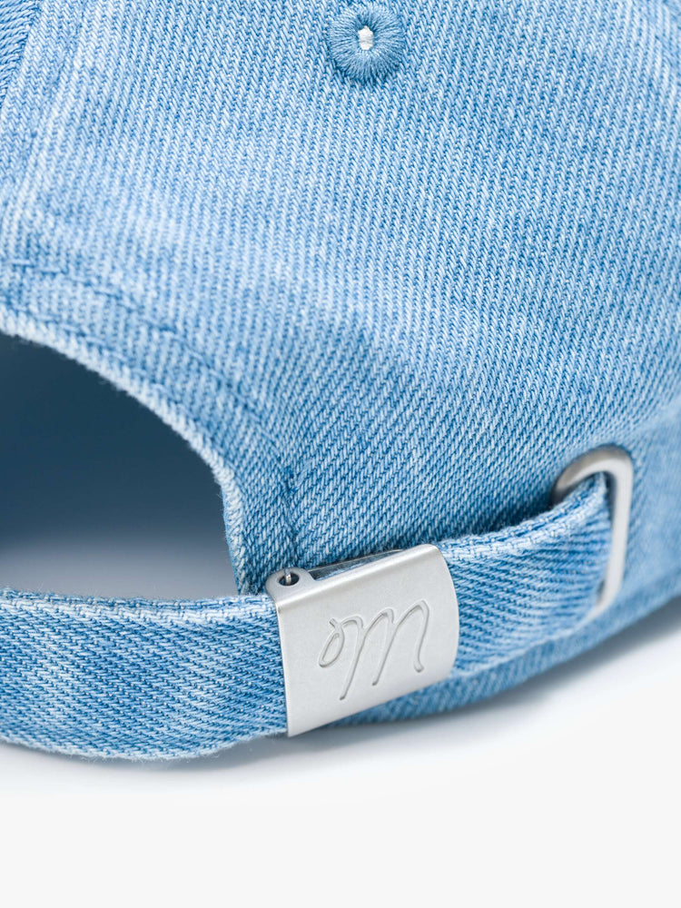 Flat swatch of a dad hat designed in light blue denim with MOTHER's name embroidered in white cursive on the front.